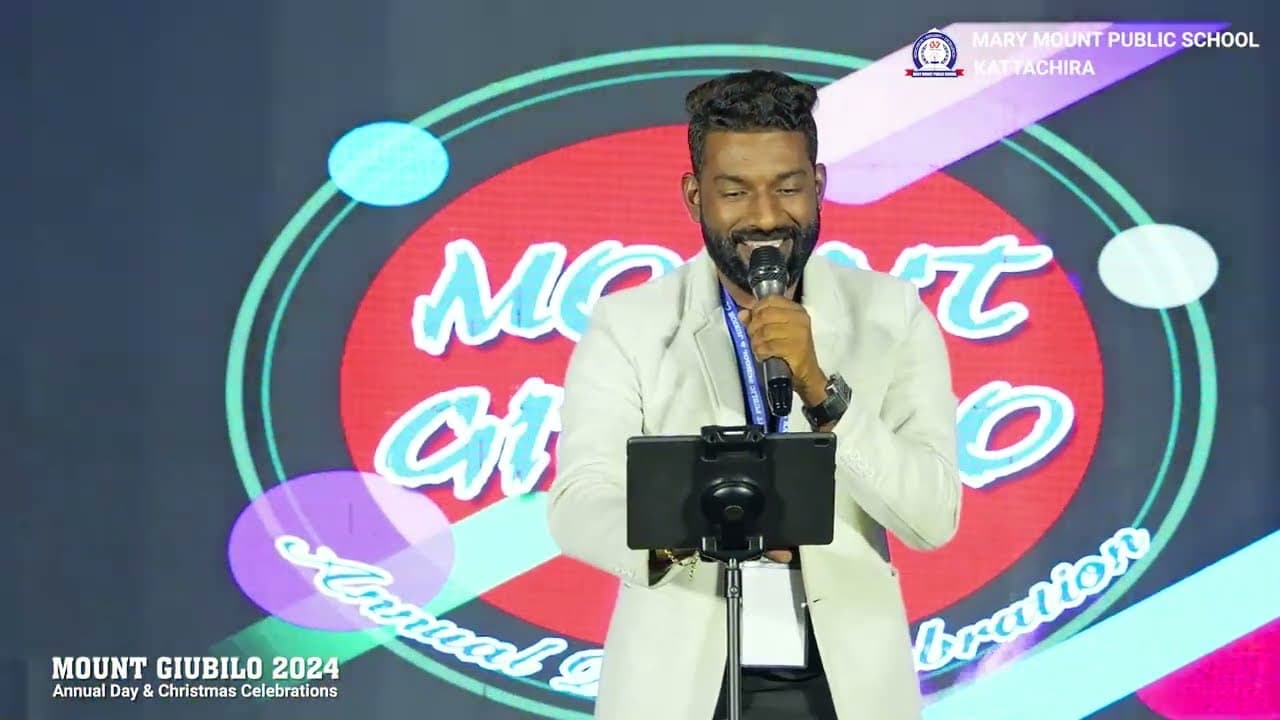 Arun Guinness performing with a microphone on the Mary Mount Public School annual-day stage