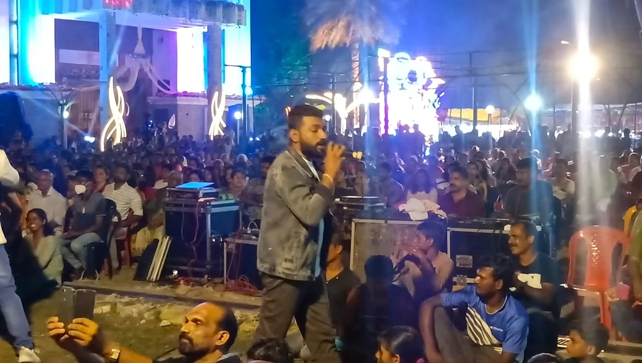 Arun Guinness singing to an outdoor audience at an evening event