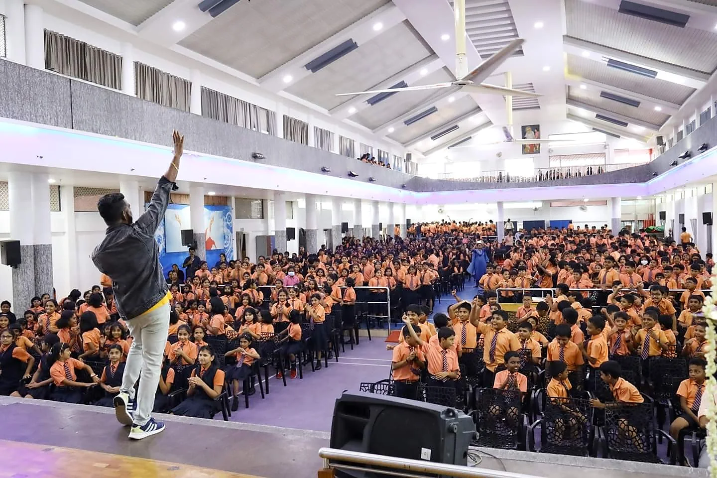 Arun Guinness facing a full school auditorium from the stage
