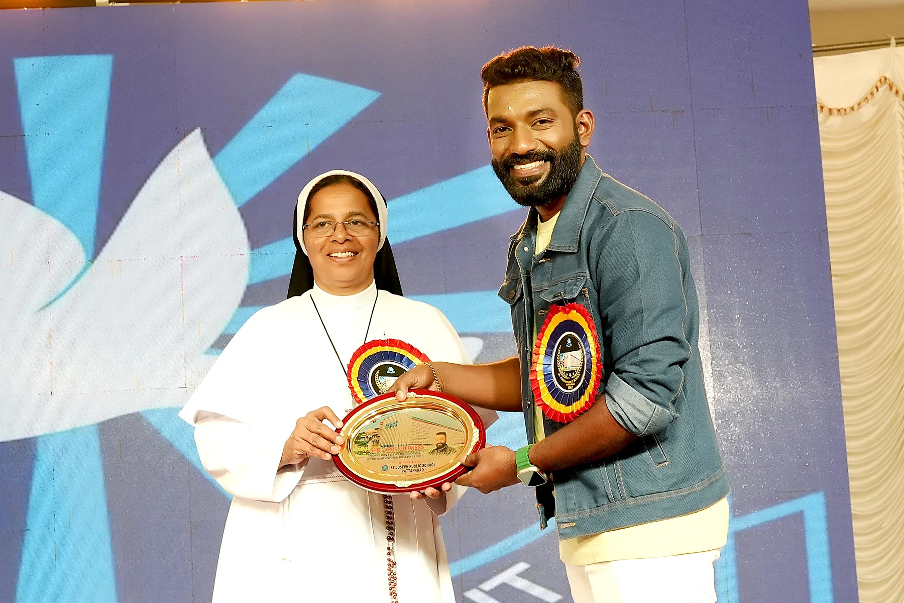 Arun Guinness receiving a commemorative plaque from a school representative